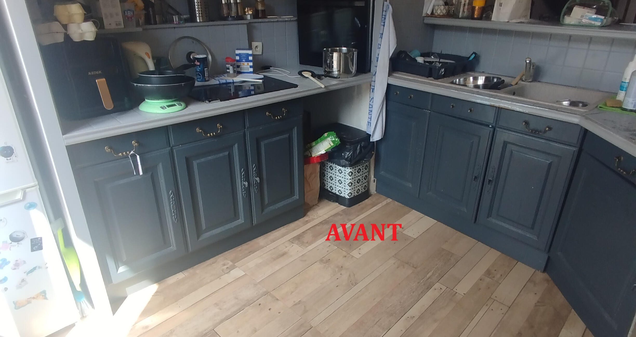 Cuisine avant rénovation : façades foncées, plan de travail clair et ancien évier.