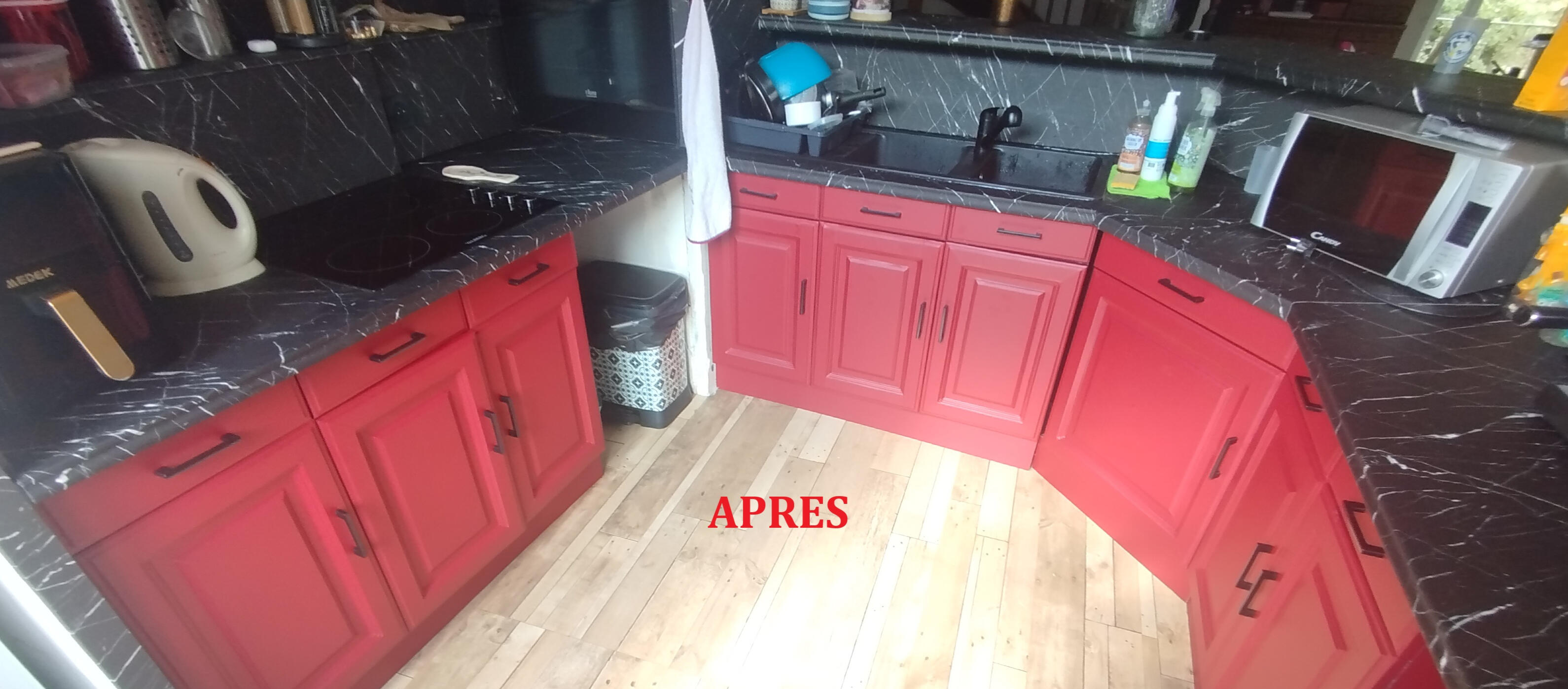 Cuisine après rénovation avec Cover Styl : façades rouges et surfaces effet marbre noir.