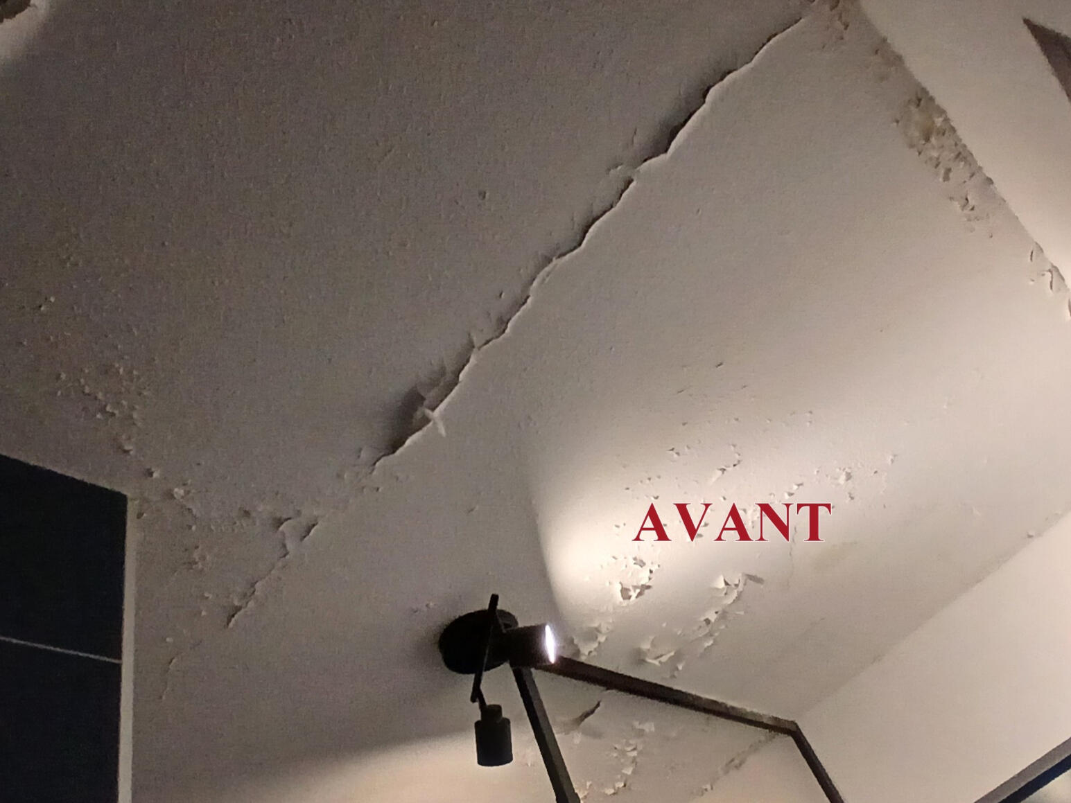 Photo avant de la rénovation d’un plafond de salle de bains abîmé, avec peinture écaillée.